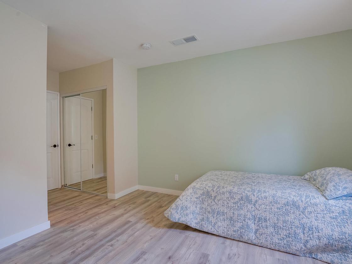 A minimalist bedroom with a simple bed and wooden flooring.