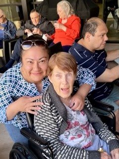 A group of people posing together indoors, including a person in a wheelchair.