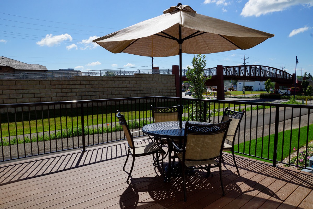 A sunny outdoor patio with a table, chairs, and an umbrella.