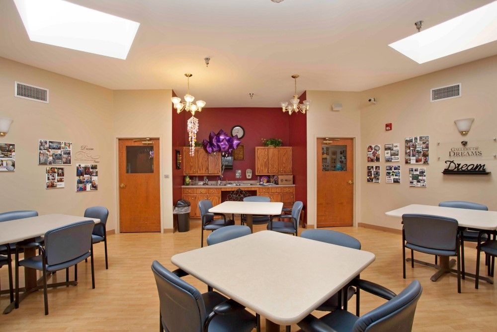 A communal space with tables and chairs, featuring a small kitchen area and decorative elements.