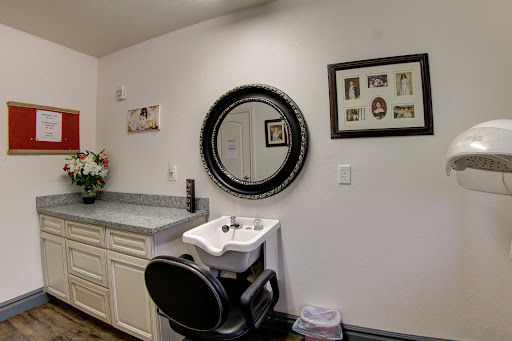 A modern hair salon setup with a circular mirror, sink, and decorative elements on the wall.