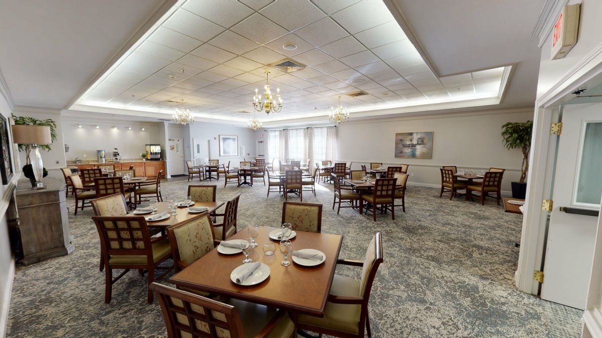 An empty dining room with neatly set tables and a chandelier.