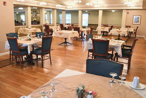An elegant dining area with neatly arranged tables and chairs, featuring a wooden floor and soft lighting.