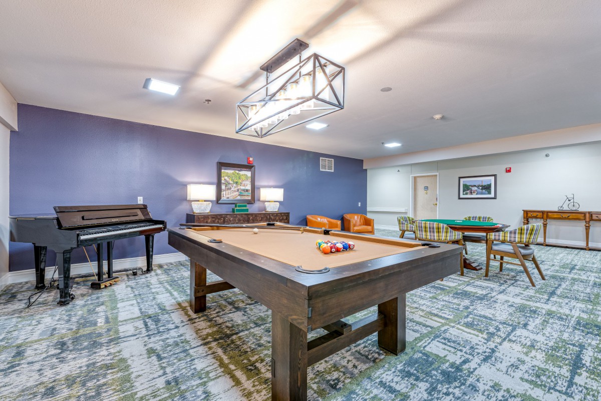 A stylish game room featuring a pool table, piano, and comfortable seating.