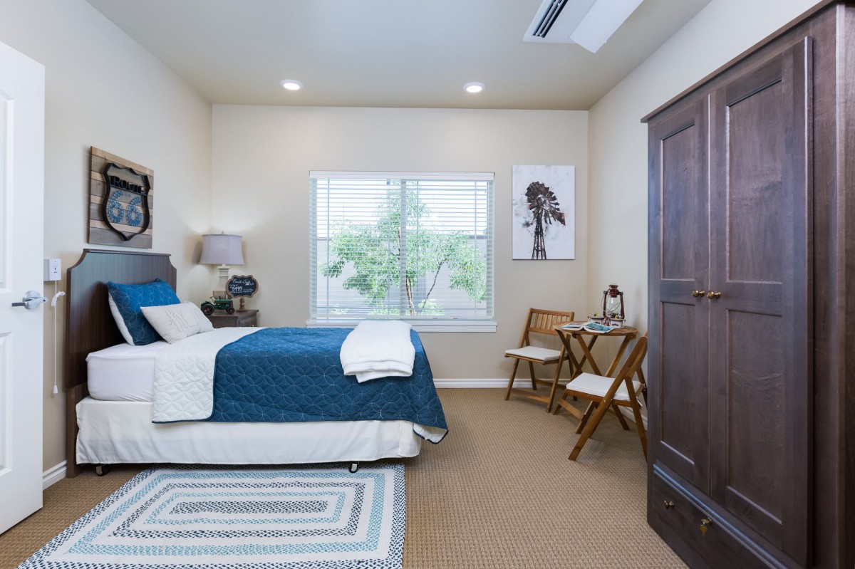 A modern bedroom with blue bedding, a window, and wall art.