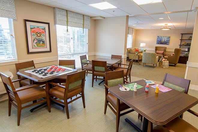 A cozy community room with tables, chairs, and a partially completed puzzle.
