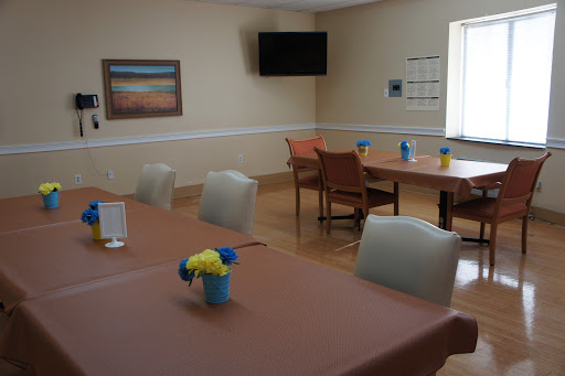 A spacious and inviting dining area featuring tables set for meals, decorative flowers, and a television.
