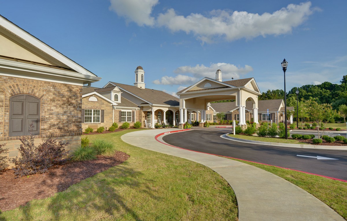 A stately building with an elegant entrance and manicured landscaping under a partly cloudy sky.