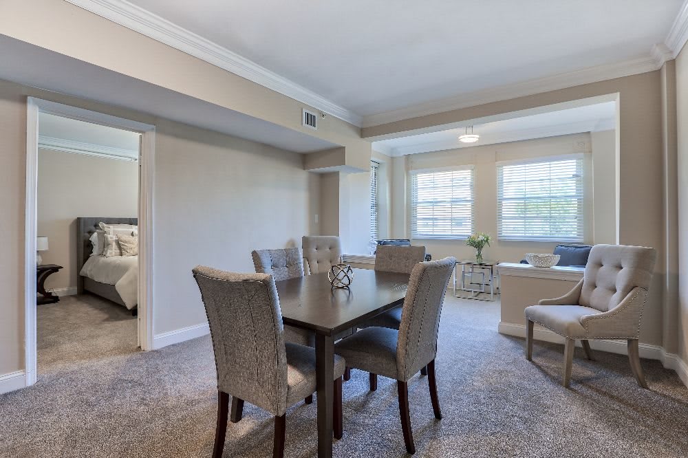 A cozy dining and living area featuring a table with chairs, large windows, and elegant decor.