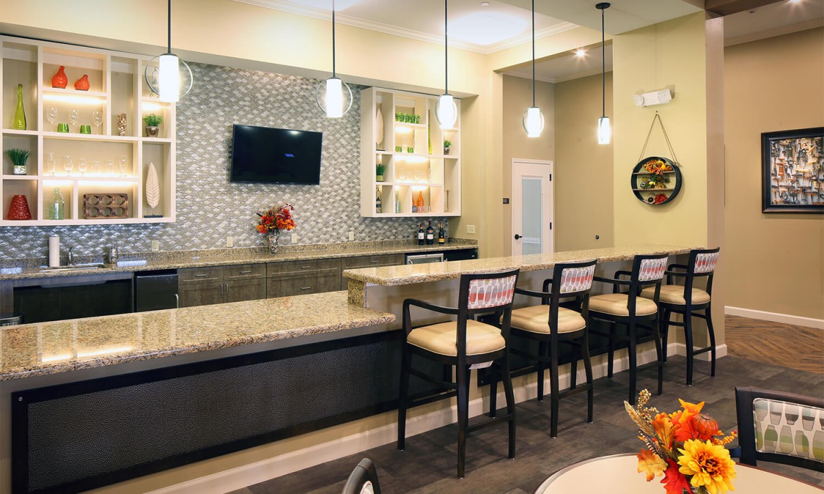 A modern bar interior with a sleek counter, comfortable seating, and ambient lighting.