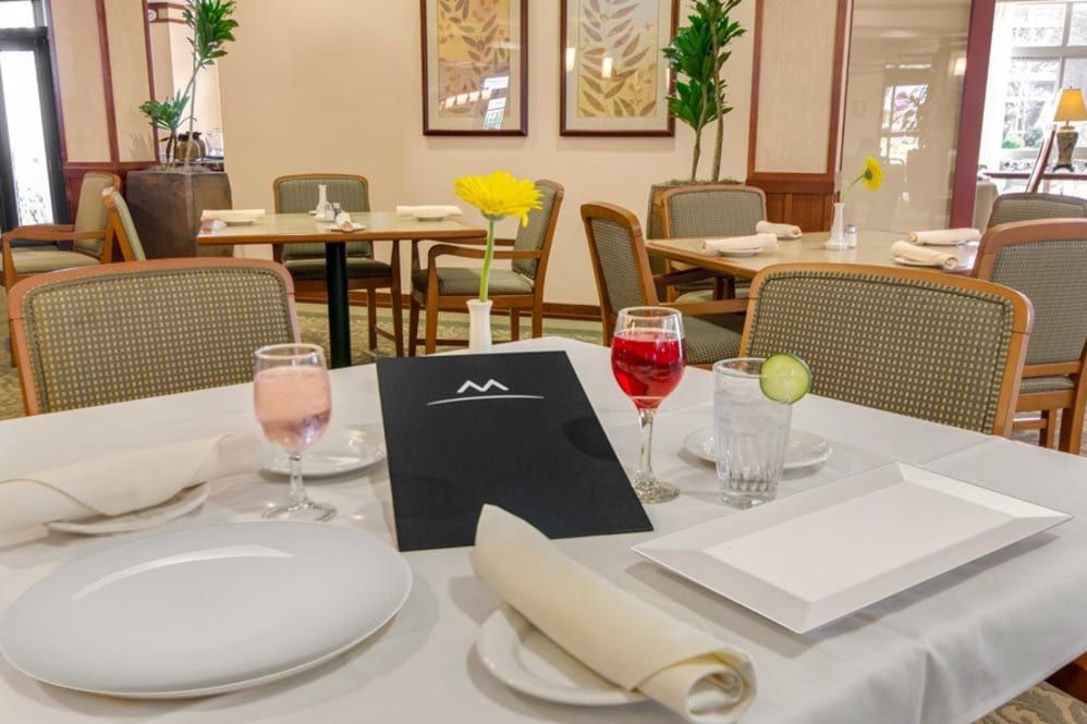 A neatly set table in a restaurant, featuring a menu and glasses with drinks.