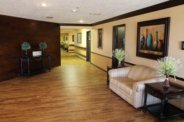 A spacious lobby with a sofa and decorative artwork, featuring warm wood flooring.