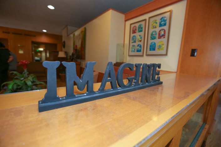 A decorative sign reading 'IMAGINE' placed on a wooden surface in a cozy interior setting.
