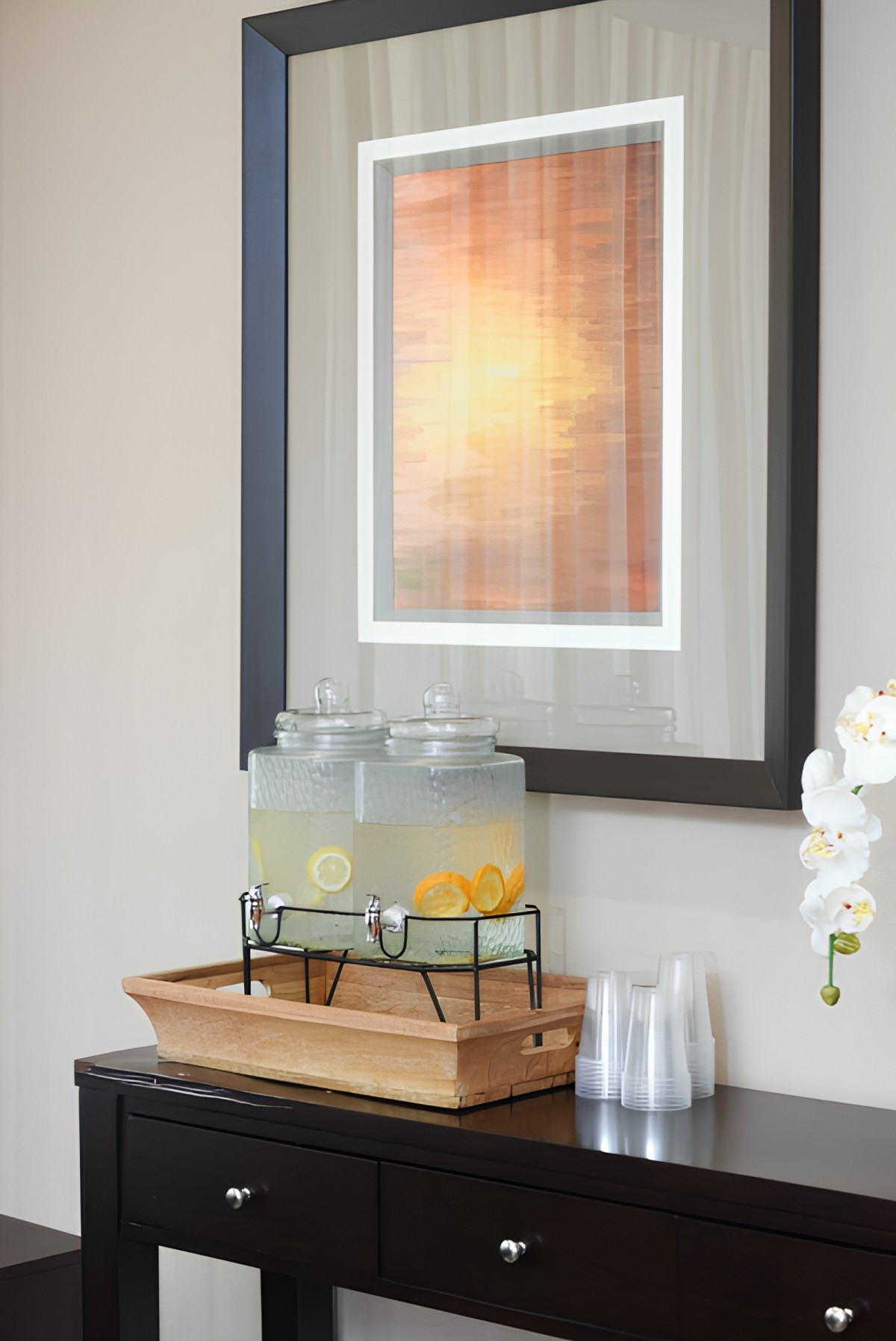 A refreshment station featuring lemonade in dispensers, adorned with lemons, set against a backdrop of framed artwork.