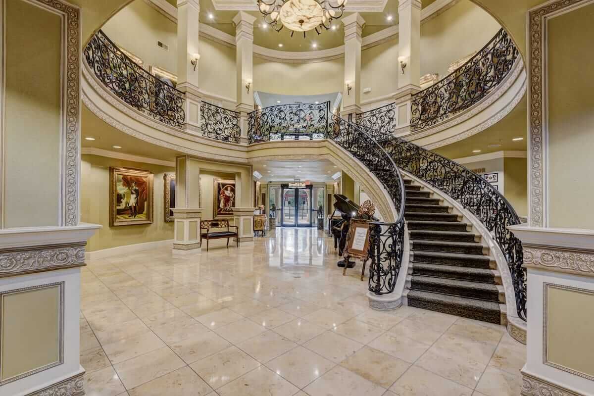 A luxurious lobby featuring a grand staircase, marble flooring, and elegant decor.