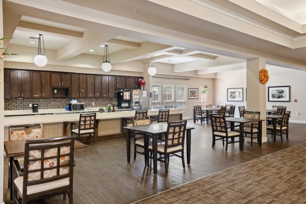 A spacious and modern dining area with tables and chairs, adjacent to a kitchen.
