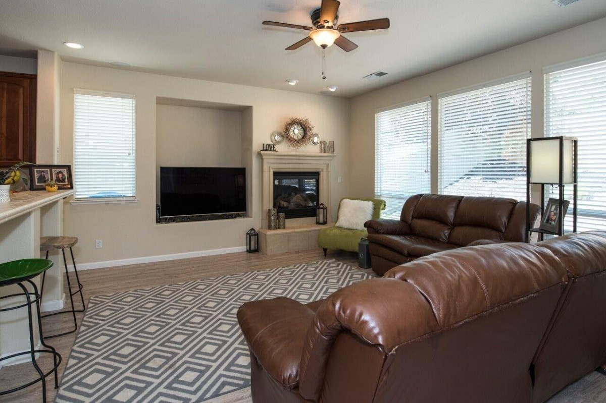 A cozy living room featuring leather sofas, a fireplace, and large windows.