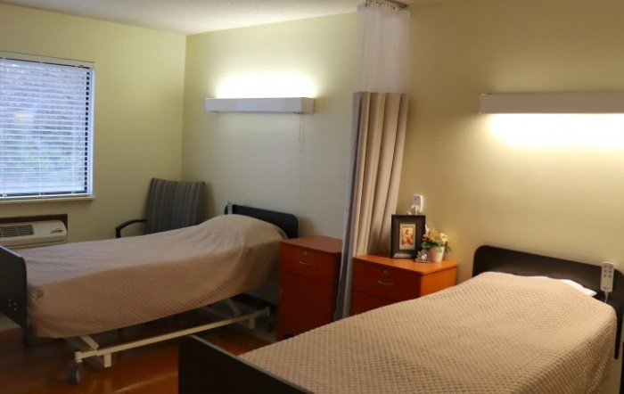 A hospital room with two beds and a curtain divider, featuring minimalist decor.