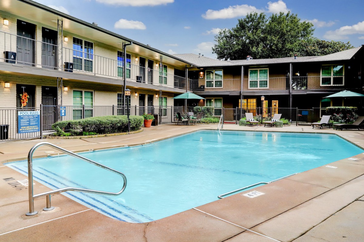 An outdoor swimming pool at an apartment complex on a sunny day.