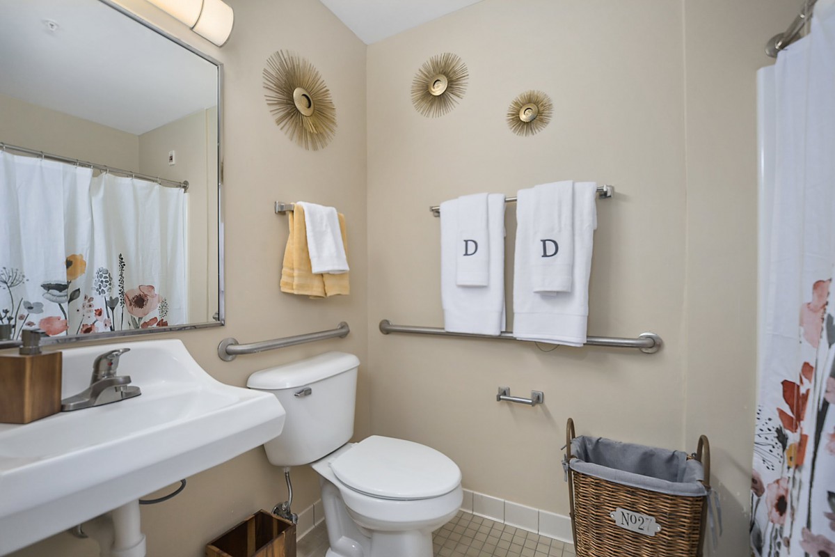 A well-organized bathroom with wall decor, a sink, toilet, and neatly hung towels.
