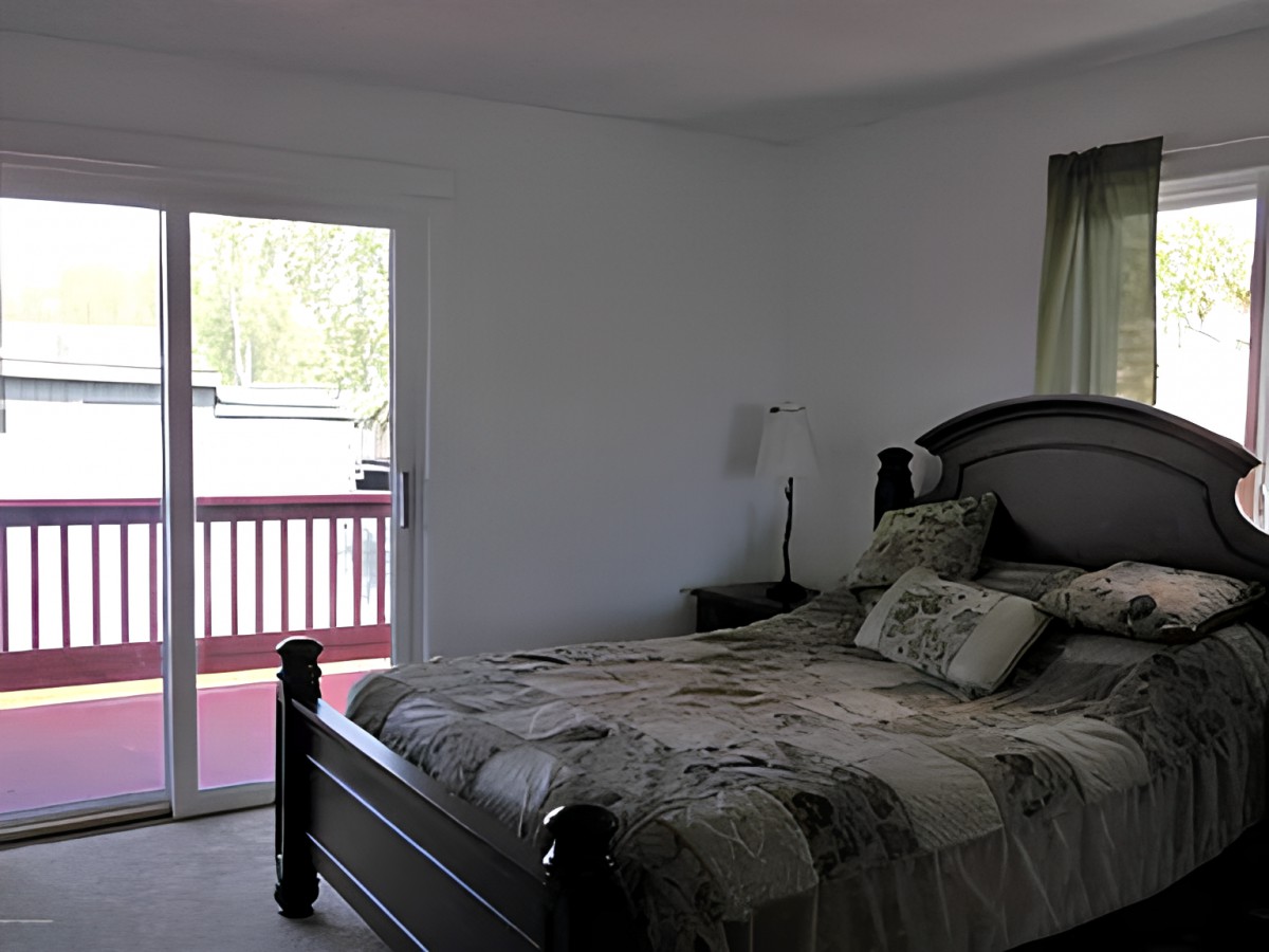 A cozy bedroom with a large bed and natural light coming through a sliding glass door.