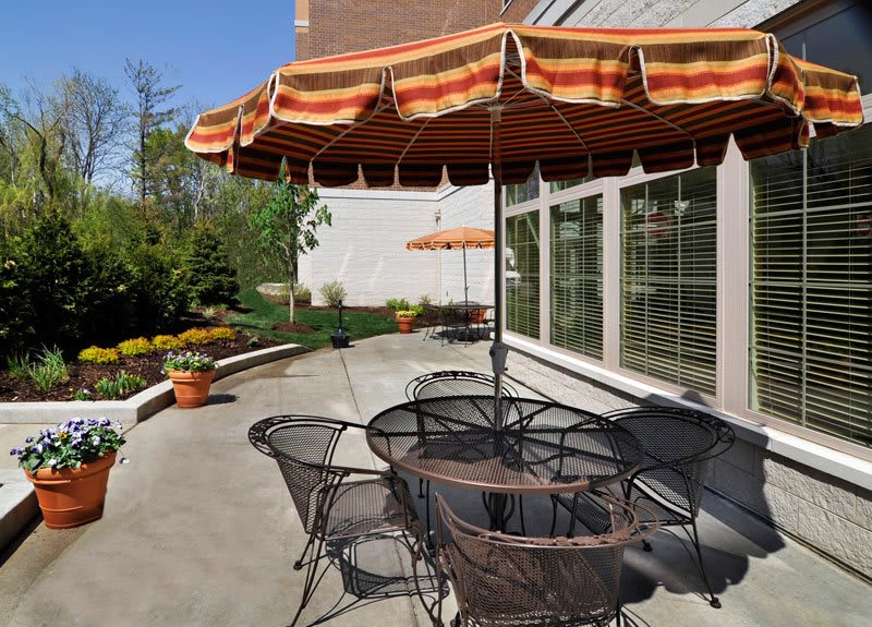 A cozy outdoor patio with chairs, a table, and umbrellas on a sunny day.