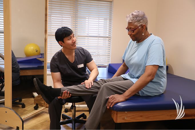 A healthcare professional assists a patient during a physical therapy session.