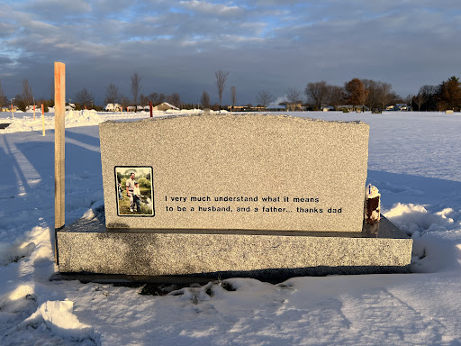 A serene winter setting featuring a memorial stone dedicated to a loved one.