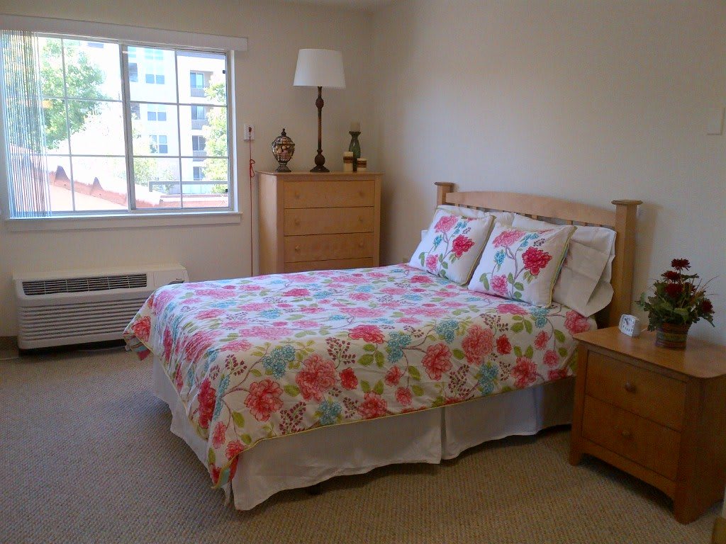 A cozy bedroom with a floral bedspread and wooden furniture.