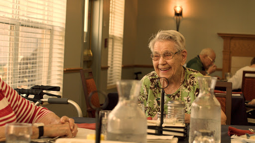 Two elderly individuals sharing a joyful conversation in a warm indoor setting.