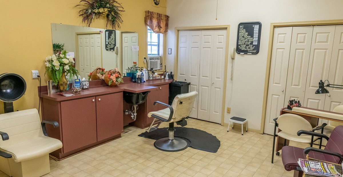 A cozy hair salon with a single barber chair, counter, and mirrors.