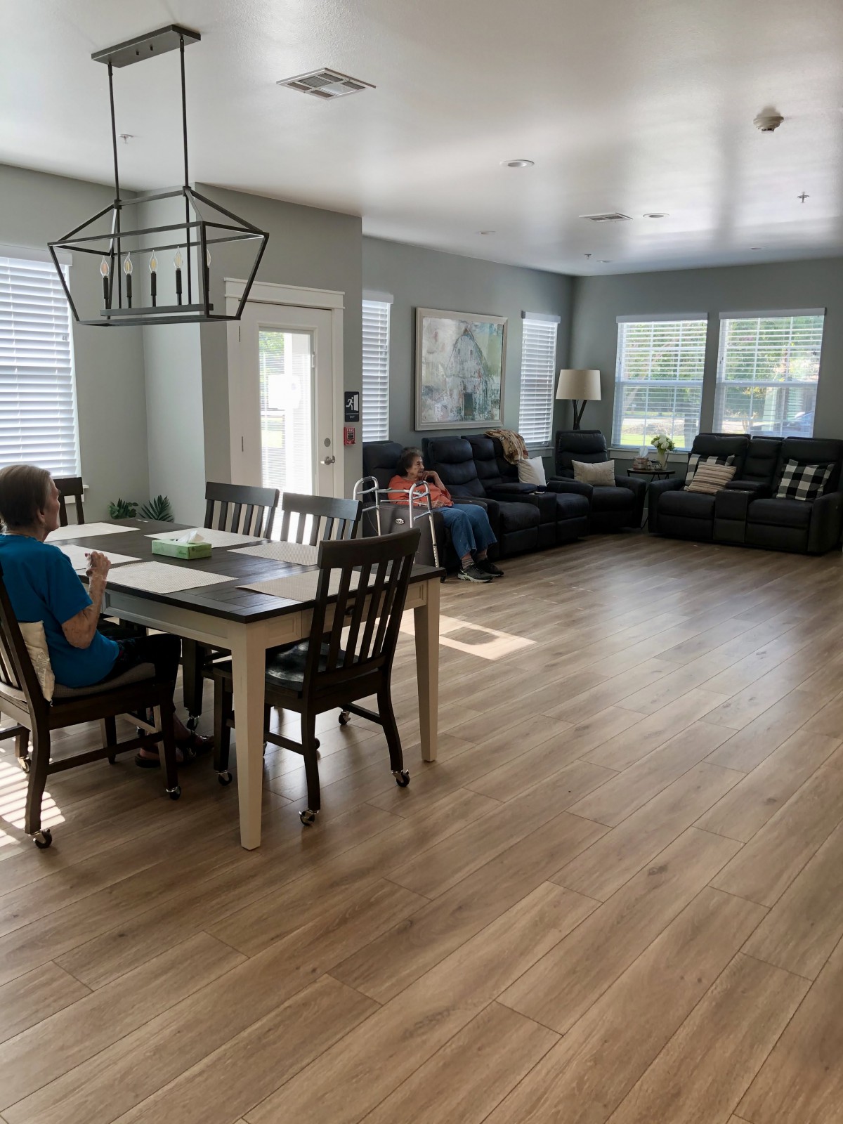 A spacious living room with a dining table, chairs, and a seating area set on a wooden floor.