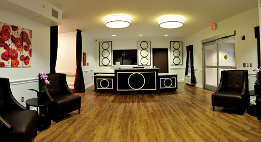 A stylish modern lobby featuring a unique black and white reception desk, complemented by wooden flooring and contemporary lighting.