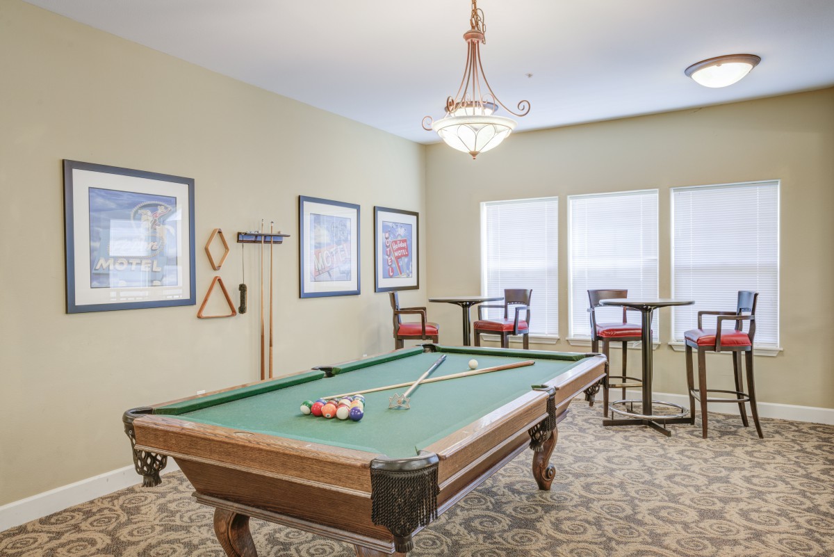 A well-lit game room featuring a pool table and high-top seating.