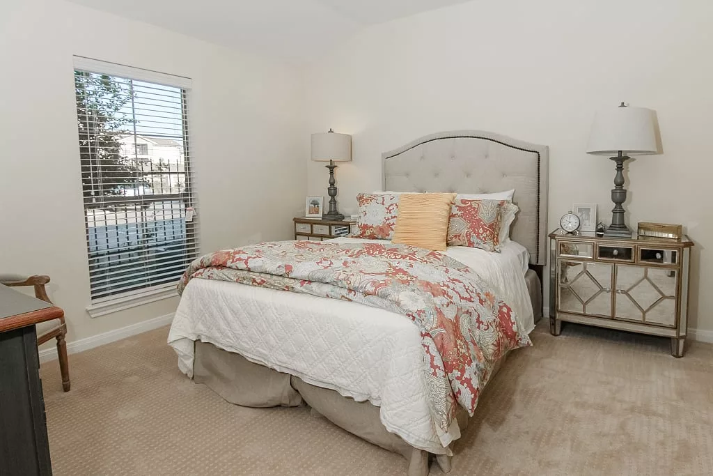 A cozy and elegantly decorated bedroom with a comfortable bed, stylish lamps, and a large window.