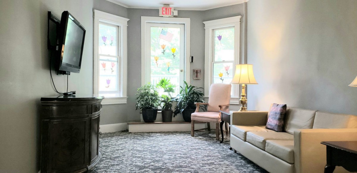 A cozy living room with large windows, plants, and comfortable seating.