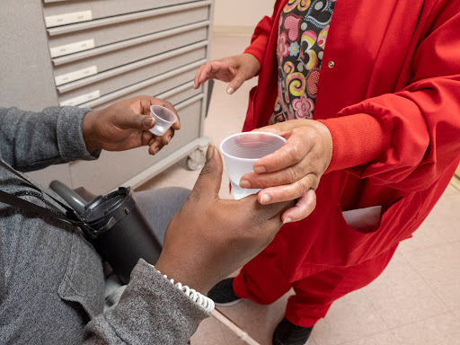 A healthcare professional assisting a patient with medication in a hospital setting.