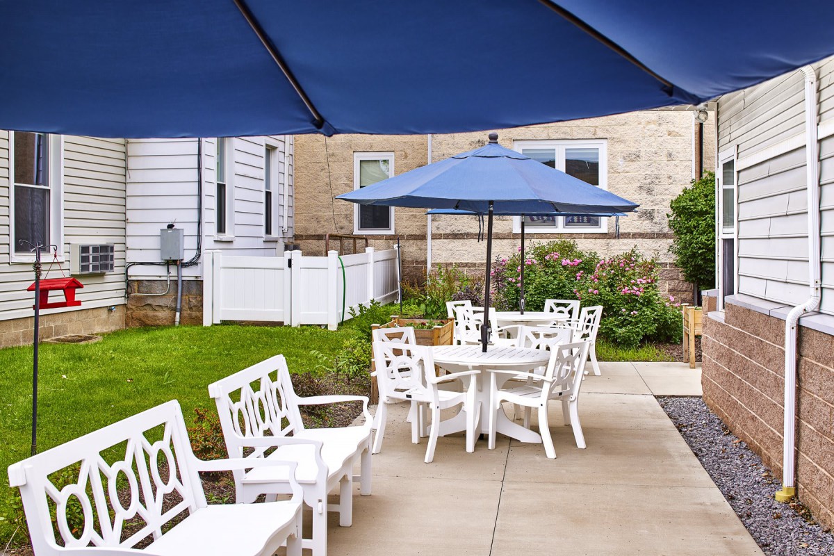 Outdoor patio area with white furniture and blue umbrellas.
