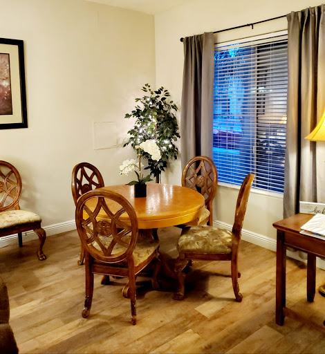 A cozy living room featuring a wooden dining set, soft lighting, and decorative plants.