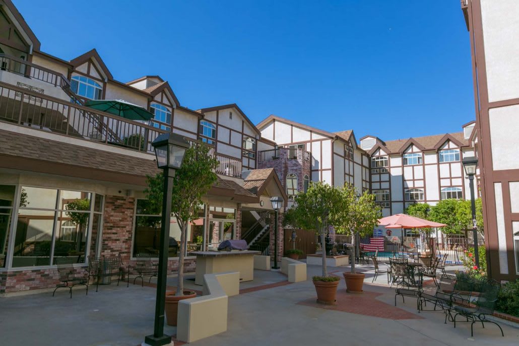 A view of a building with a patio area and trees on a clear day.