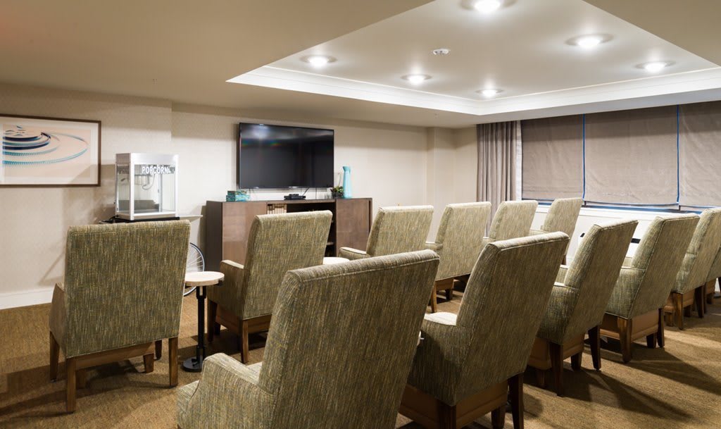 A well-equipped conference room with multiple chairs facing a large display screen.