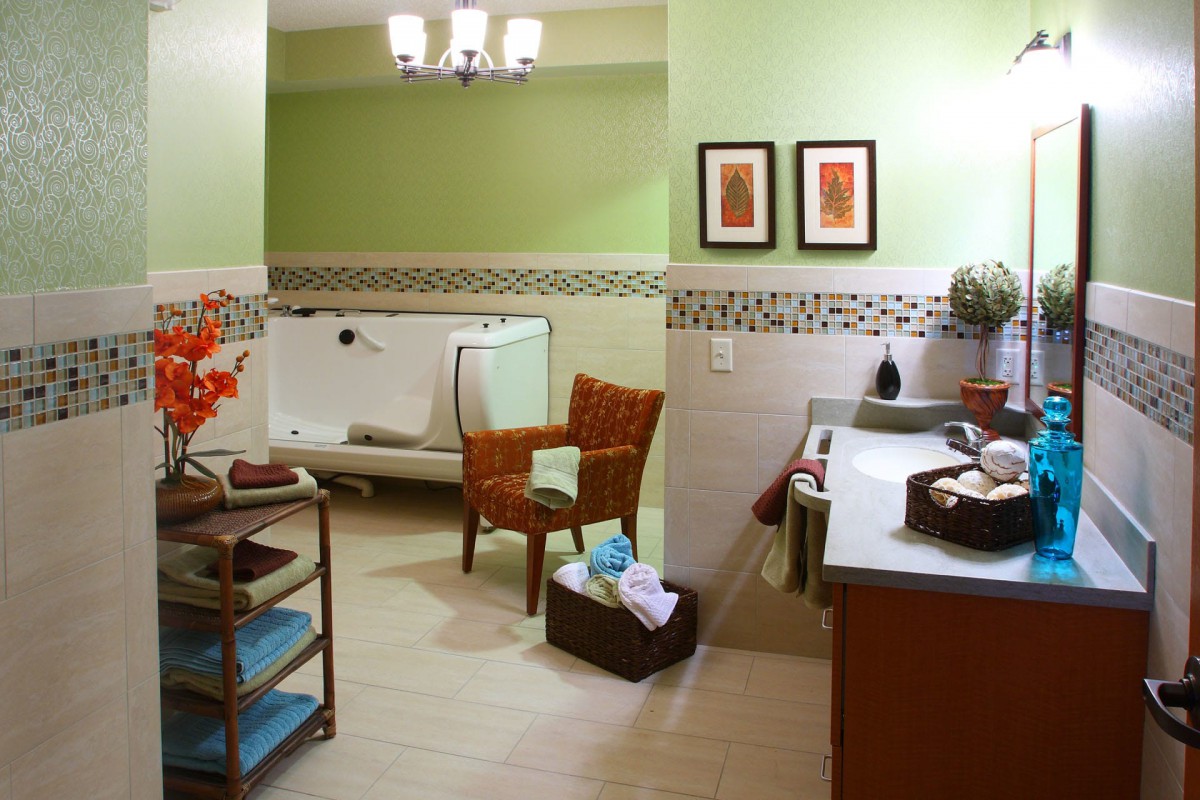 A modern bathroom with green walls, featuring a bathtub, chair, and stylish decor.