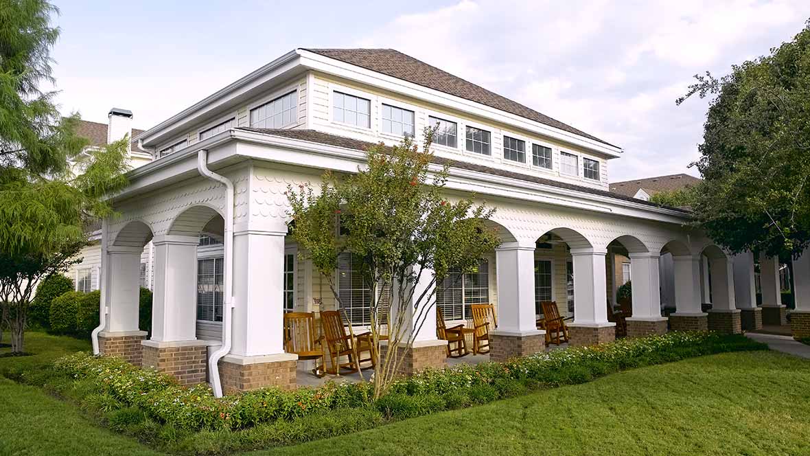 A two-story suburban house with a spacious porch and well-maintained lawn.