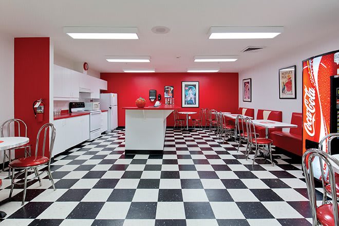 A retro-style diner with red and white decor, featuring a classic checkered floor and booth seating.