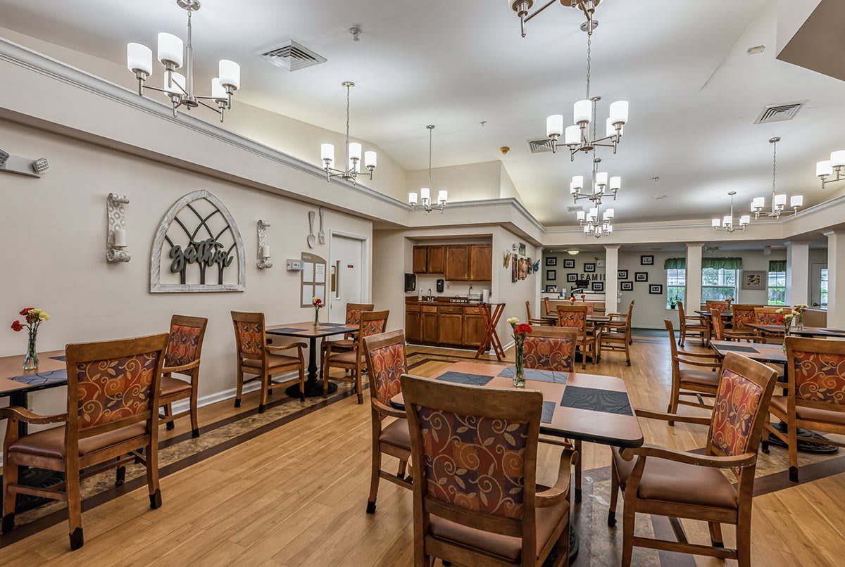 A well-lit dining room with wooden tables and chairs, featuring elegant lighting and decor.