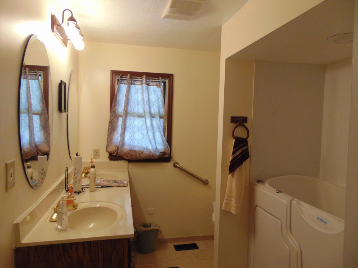 A cozy bathroom with a single sink, mirror, and window with curtains.