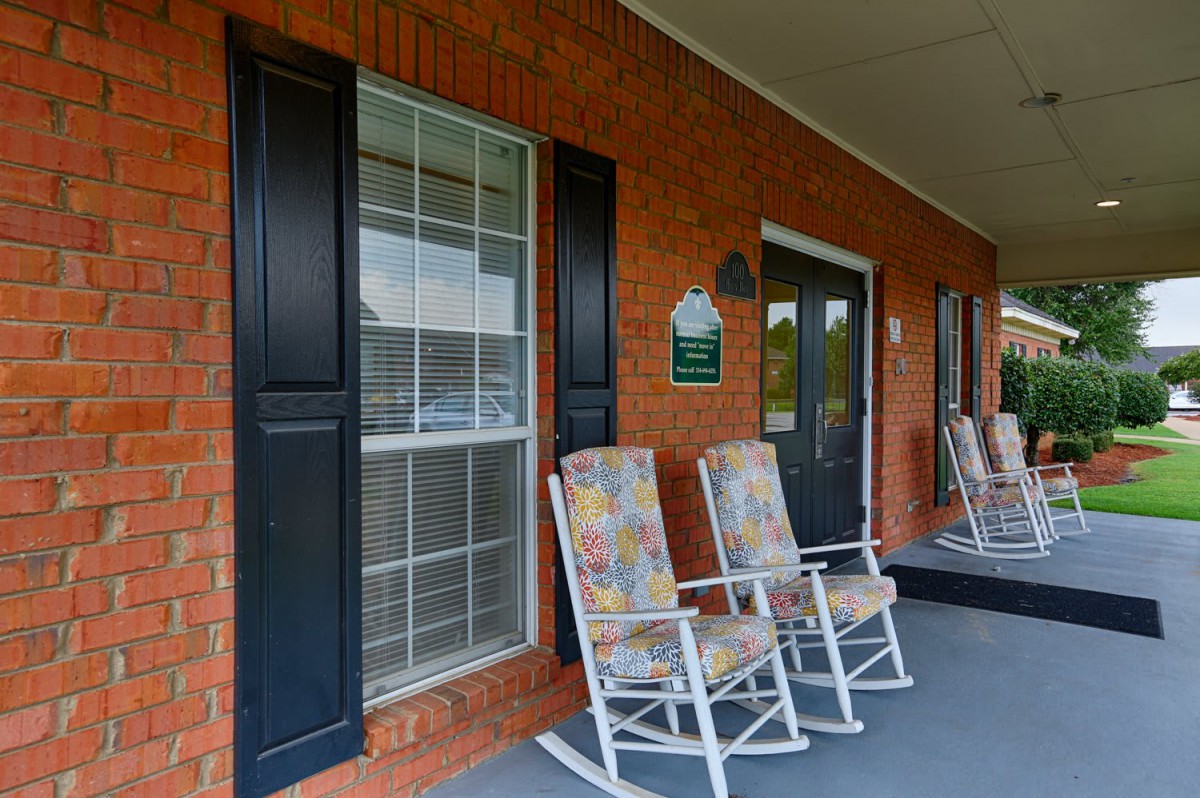 A cozy porch with rocking chairs set against a brick wall.