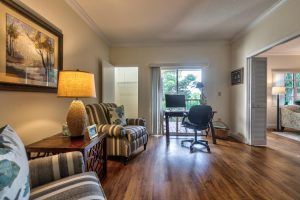 A cozy living room with armchairs, a desk, and a sliding glass door leading outside.