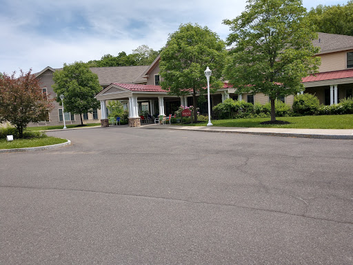 A serene view of a building set amidst lush greenery, with a well-maintained road leading to its entrance.