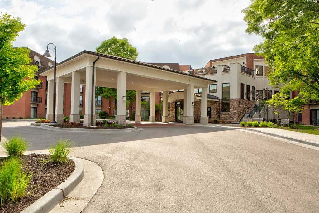 A modern building with a covered entrance and a circular driveway.